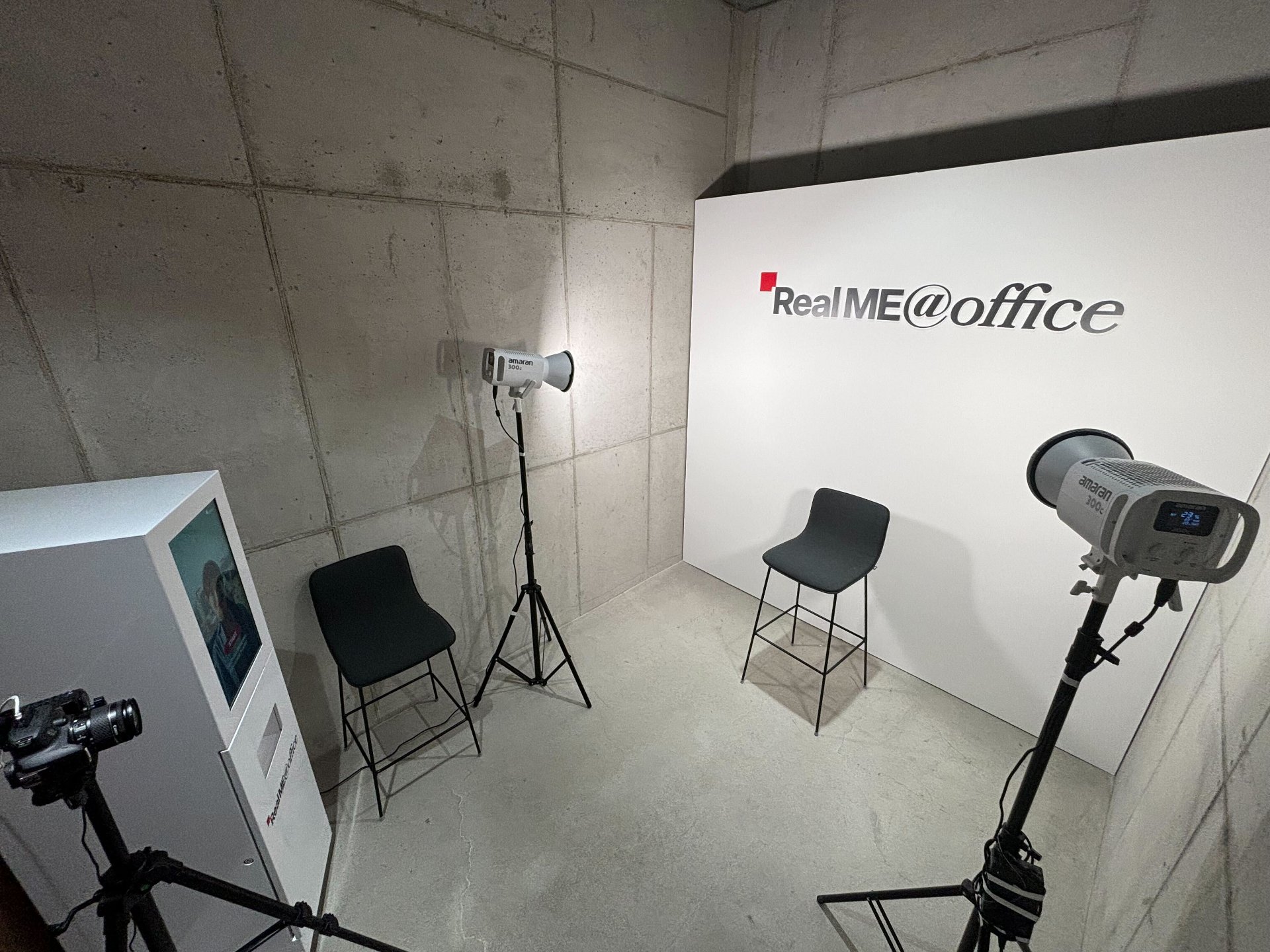 브랜드 배경판과 DSLR 카메라, 조명을 갖춘 스튜디오형 촬영 공간